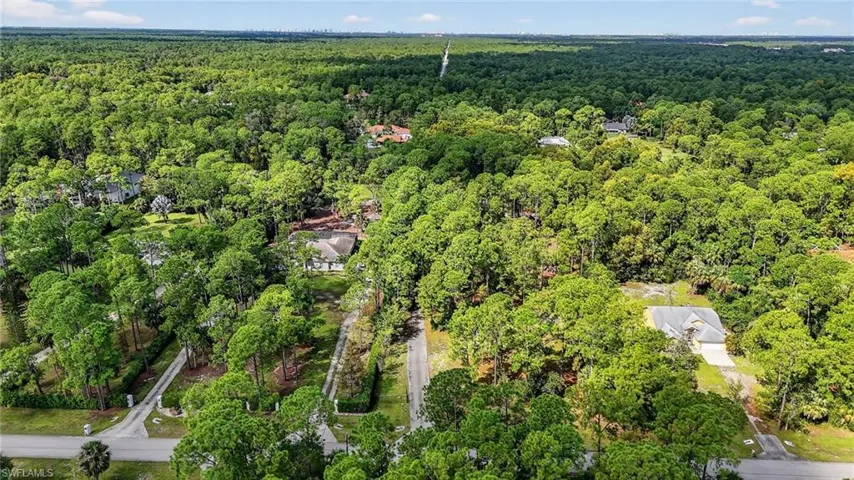 Aerial view of property and surrounding area with a forest