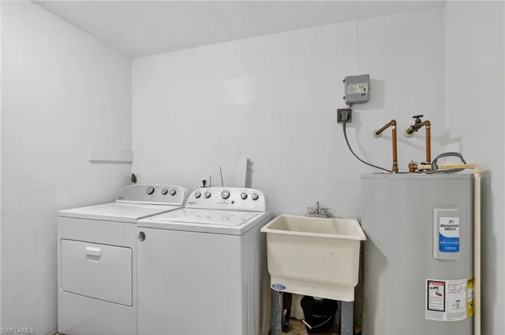 Washroom featuring electric water heater and washing machine and clothes dryer