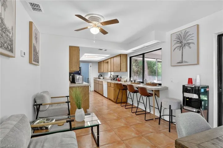 Kitchen with light countertops, light tile patterned floors, a ceiling fan, a breakfast bar area, and white dishwasher