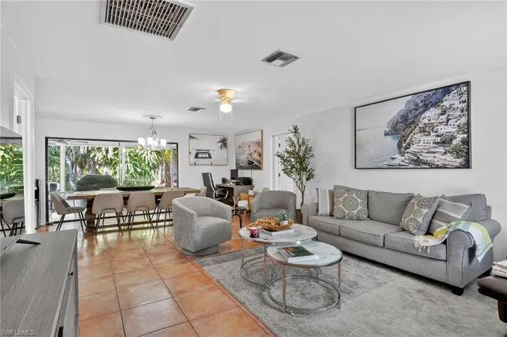 Living room featuring light tile patterned flooring, a chandelier, and a ceiling fan