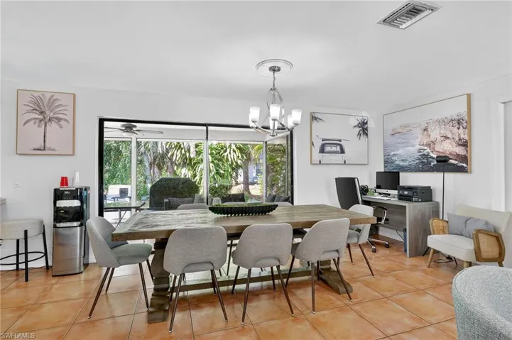 Dining area with a chandelier, light tile patterned floors, and a desk
