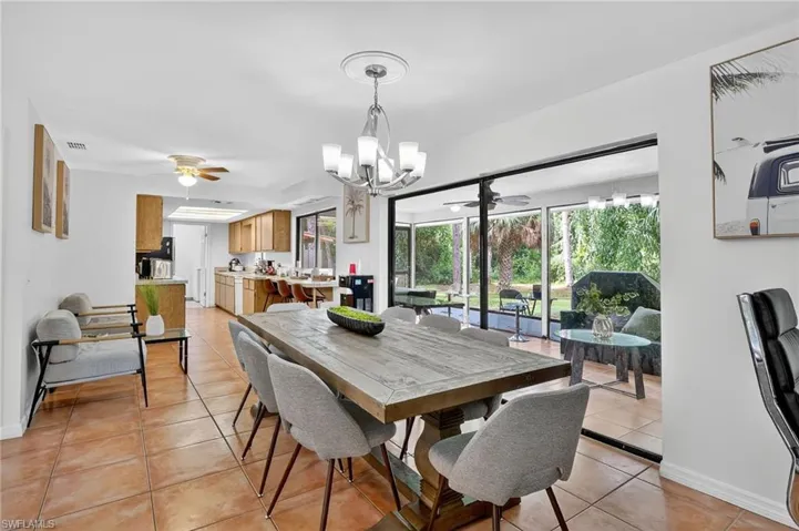 Dining space with ceiling fan, a chandelier, and light tile patterned floors