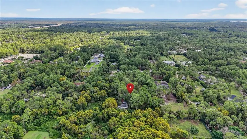 Aerial view of property and surrounding area with a forest
