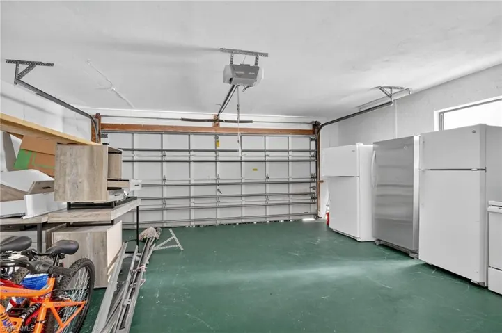 Garage featuring freestanding refrigerator and a garage door opener
