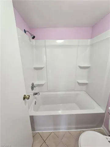 Bathroom with tub / shower combination and light tile patterned flooring