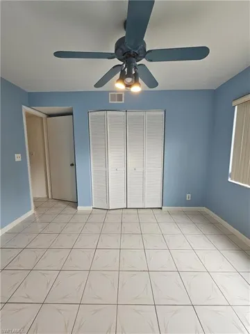 Unfurnished bedroom with a ceiling fan, a closet, and light tile patterned floors