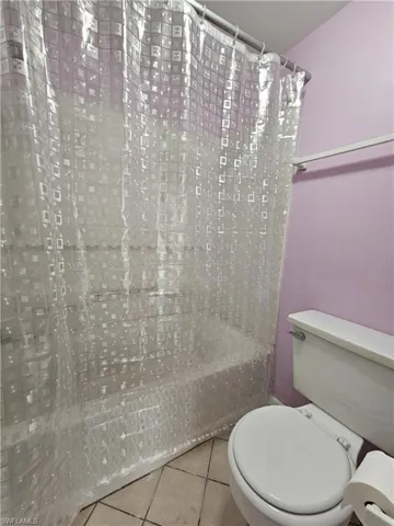 Full bath featuring shower / tub combo with curtain and tile patterned flooring