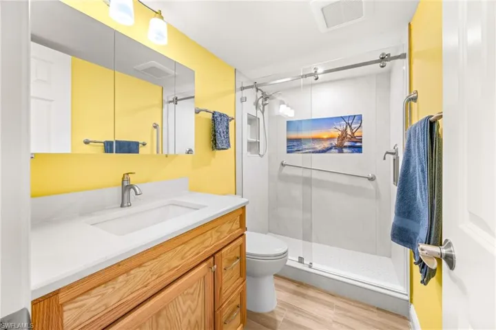 Main bathroom with tile shower, glass shower door, new vanity, tile flooring.