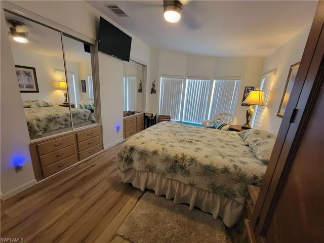 Bedroom with a ceiling fan, visible vents, and wood finished floors