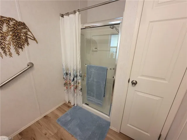 Full bathroom featuring a stall shower and wood finished floors
