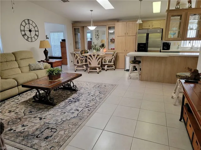 Living room featuring vaulted ceiling with skylight, visible vents, and light tile patterned floors