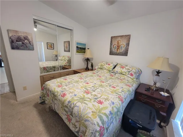 Bedroom featuring lofted ceiling, a closet, baseboards, and light colored carpet