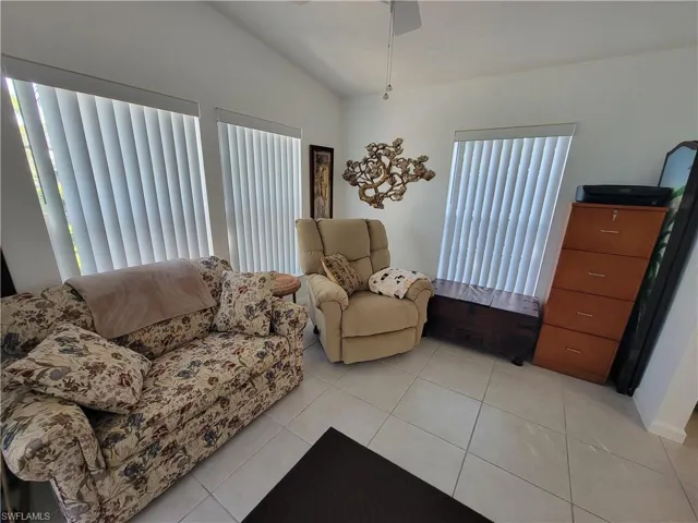 Living area featuring lofted ceiling, ceiling fan, and light tile patterned floors