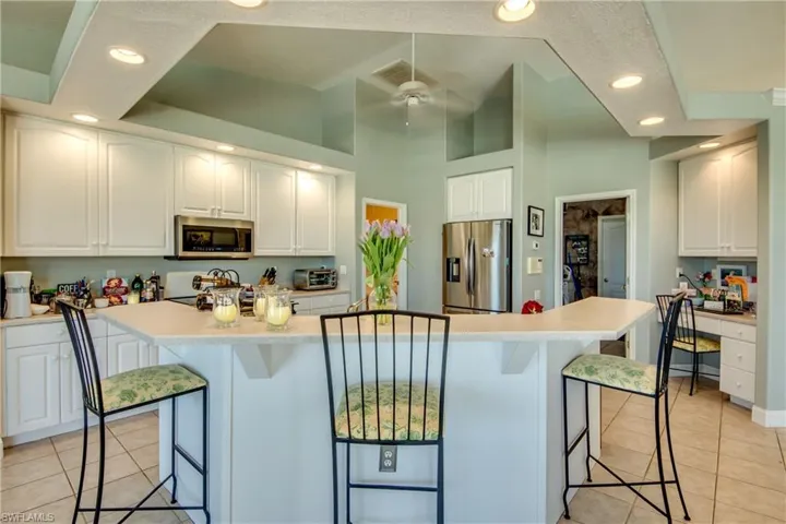 Kitchen has raised breakfast bar, built-in desk on the right, and newer stainless steel appliances. Laundry room & garage are to the right of the refrigerator.