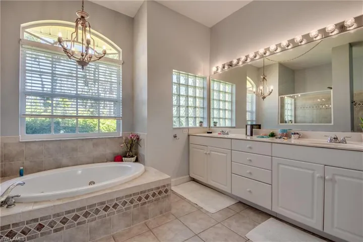 Jetted soaker tub is next to the huge vanity with dual sinks. Lots of natural light in this spacious primary bathroom. A separate water closet is to the right of the sinks.