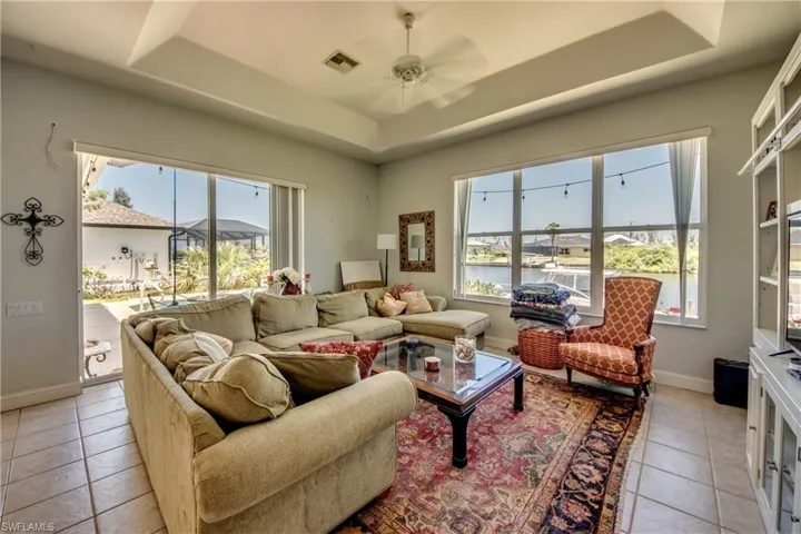 Family room has tray ceiling, tile floor, stackable sliders out to the pool, and a wonderful view of the 200' wide canal through the trio of windows.