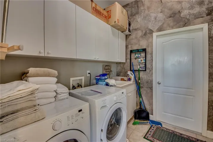 Laundry room has cabinets, a sink, and a large pantry across from the washer/dryer. Closed door accesses the garage which has lots of storage space, too.