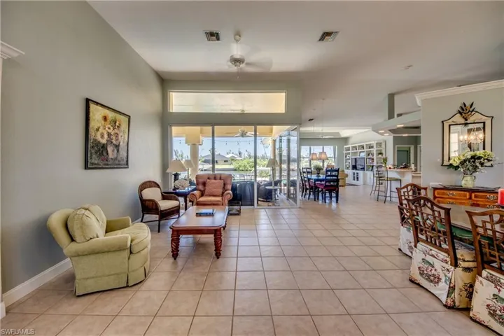 View from foyer shows living room and triple sliders beyond. Open concept with high ceilings is revealed as soon as the front door is opened.