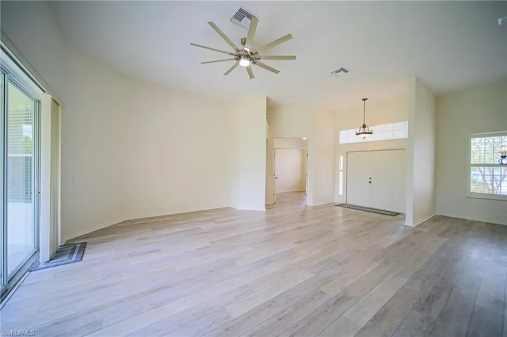 The Oversized Living Room Has Gray Wood Plank Flooring, New Ceiling Fan/Light, New Paint Throughout The Entire House, And A Triple Slider That Leads Out To The Covered Lanai!