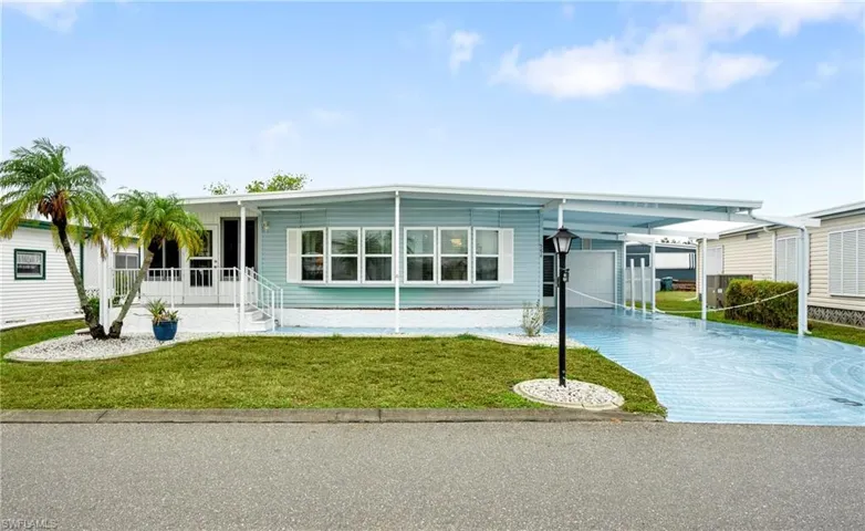 Manufactured / mobile home featuring a front lawn, driveway, a carport, and a garage