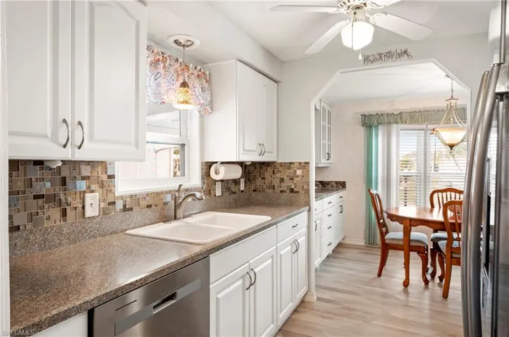 Kitchen featuring stainless steel appliances, a sink, a ceiling fan, white cabinetry, and backsplash