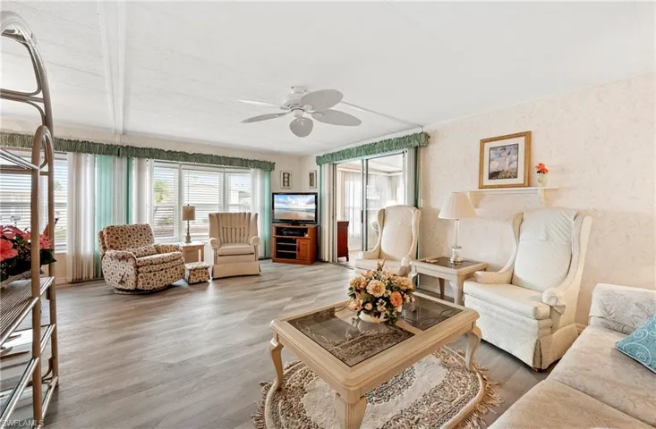 Living area featuring a ceiling fan, wood finished floors, and wallpapered walls