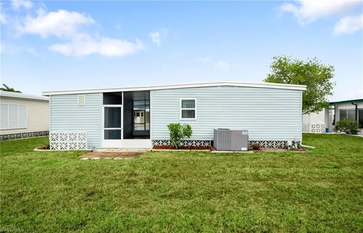 Back of property featuring central air condition unit, a sunroom, and a lawn