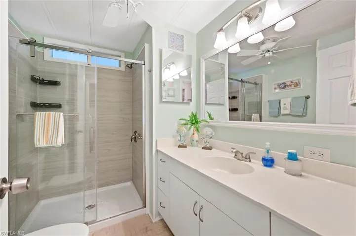 Full bathroom featuring ceiling fan, a stall shower, and vanity