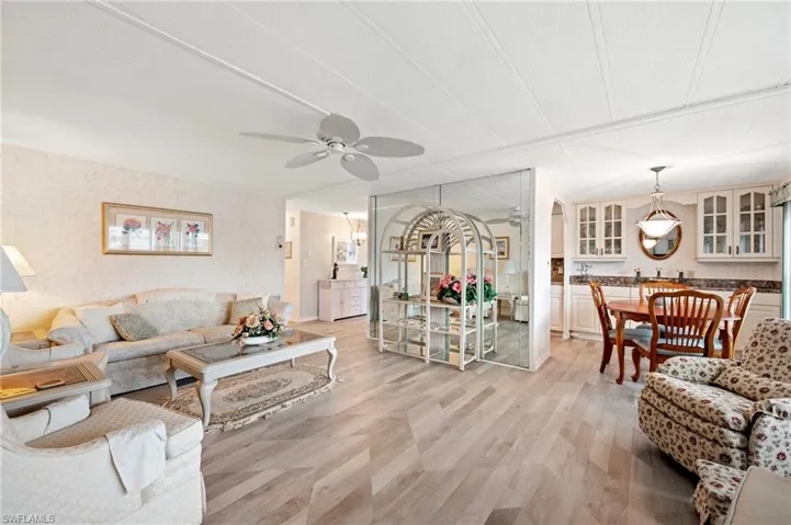 Living room with light wood-type flooring, a ceiling fan, and arched walkways