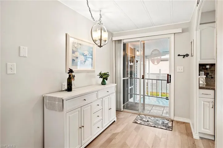 Doorway with light wood-type flooring and a chandelier