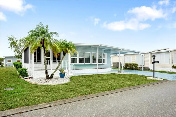 Manufactured / mobile home featuring a carport, a front yard, and driveway