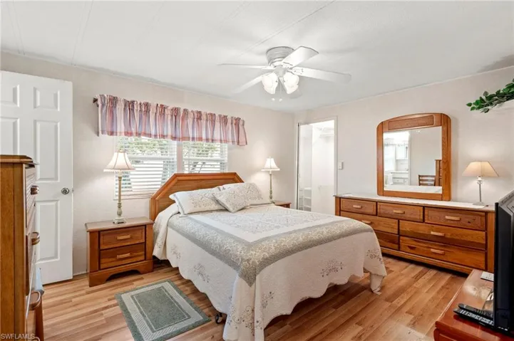 Bedroom featuring light wood finished floors, ceiling fan, arched walkways, and a spacious closet