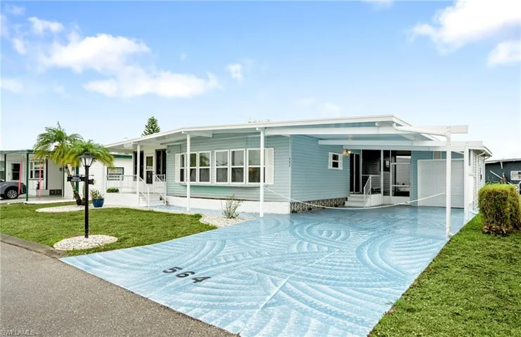 View of front of house featuring concrete driveway, a front yard, an attached carport, and entry steps