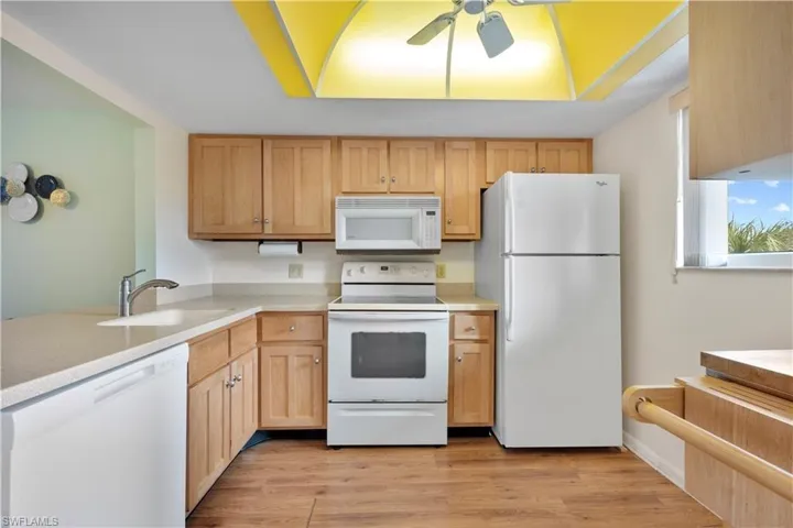 Kitchen with white appliances, light countertops, a ceiling fan, and light wood-style floors