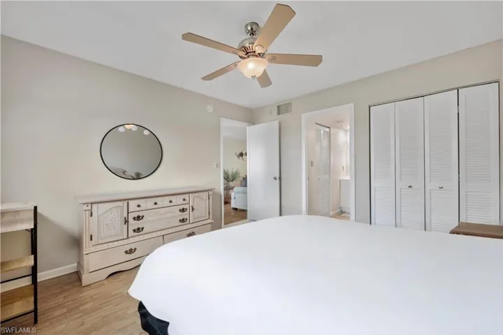 Bedroom with light wood-style flooring, ensuite bathroom, ceiling fan, and a closet