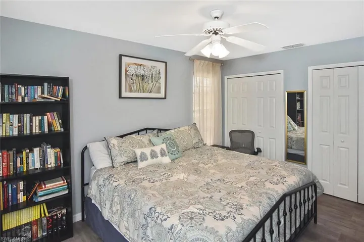 Bedroom featuring two closets, a ceiling fan, and dark wood-type flooring