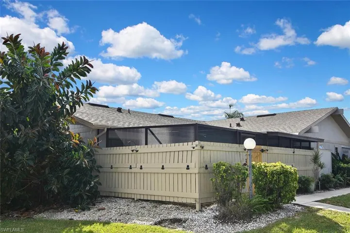 View of property exterior featuring roof with shingles and a sunroom
