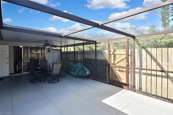 View of patio / terrace with a gate, glass enclosure, a sunroom, ceiling fan, and outdoor dining area