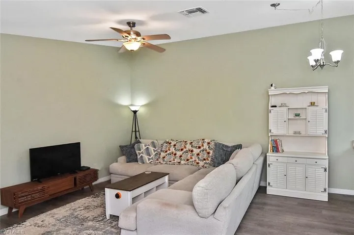 Living area featuring dark wood-type flooring, a ceiling fan, and a chandelier