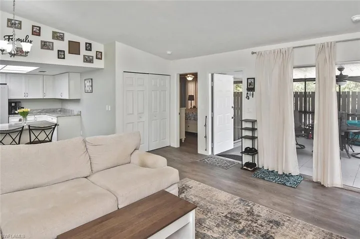 Living room featuring vaulted ceiling, dark wood-style flooring, and a chandelier