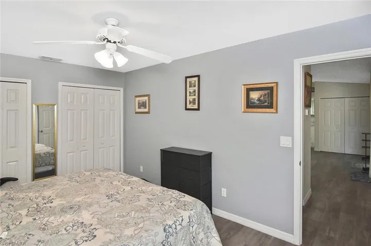 Bedroom with multiple closets, a ceiling fan, and wood finished floors