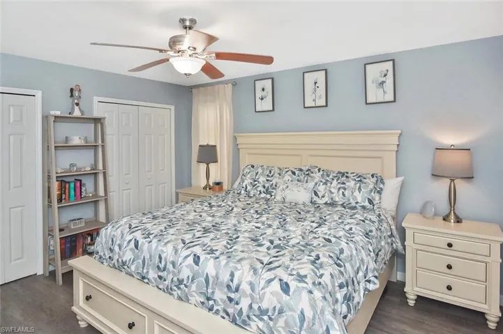 Bedroom featuring multiple closets, dark wood-type flooring, and ceiling fan