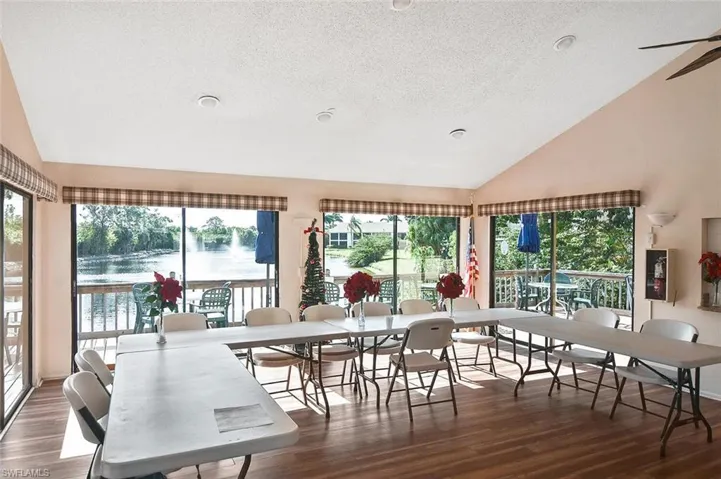 Dining area featuring lofted ceiling, plenty of natural light, a textured ceiling, dark wood-type flooring, and a water view