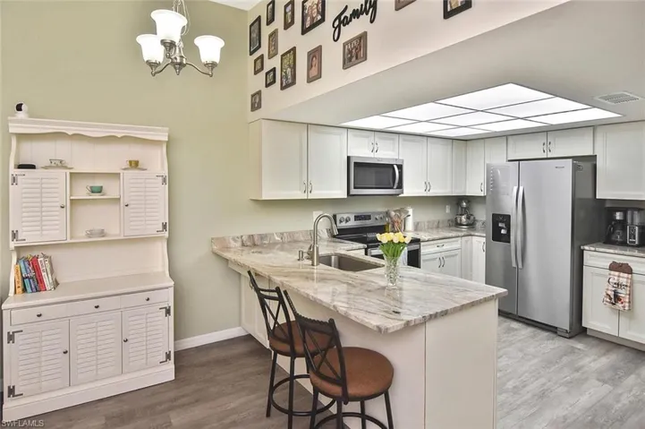 Kitchen with stainless steel appliances, white cabinets, and light wood-style flooring