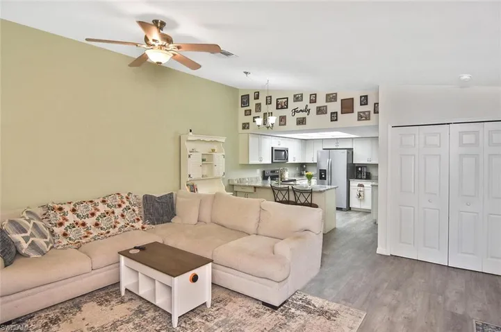 Living area featuring light wood-type flooring, a ceiling fan, and high vaulted ceiling