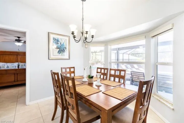 Dining area with ceiling fan with notable chandelier and light tile patterned floors