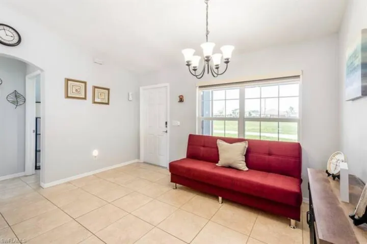Living room featuring light tile patterned flooring and an inviting chandelier