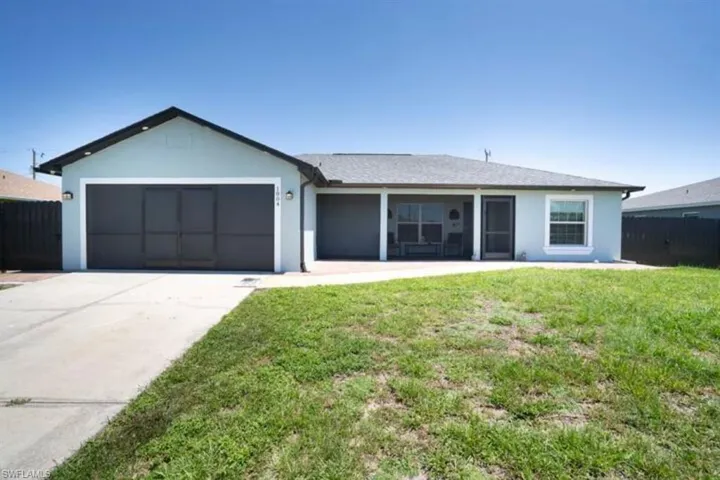 View of front of property with a garage and a front lawn