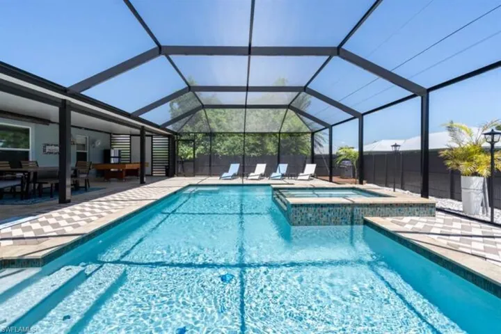 View of swimming pool featuring an in ground hot tub, glass enclosure, and a patio area