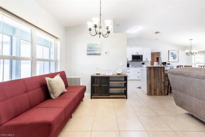 Tiled living room with lofted ceiling and a chandelier